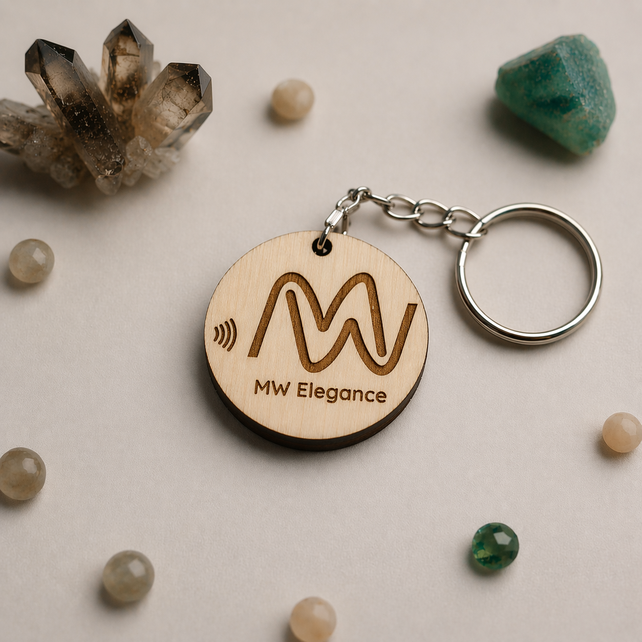 Wooden NFC keychain with 'MW Elegance' logo on a surface with crystals and stones.